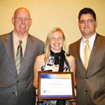 Aureus Medical employees Bill H. and Justin C. present Kristin S. the Rehab Therapy Employee of the Year plaque.
